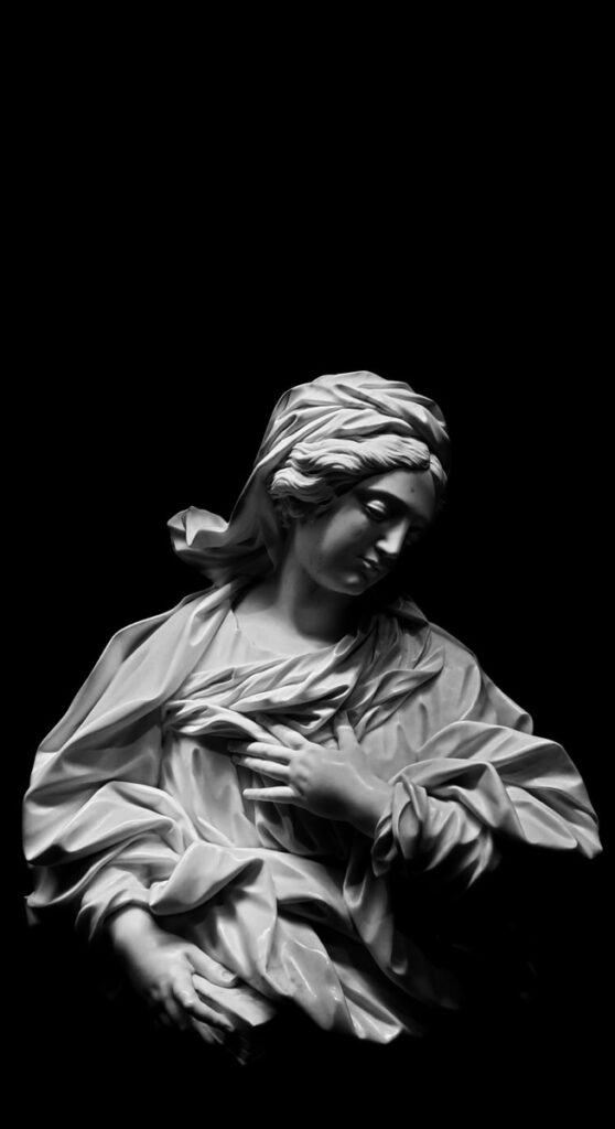 grayscale photography of woman with left hand on chest statue