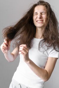 Woman struggling to brush hair.