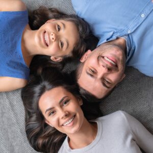 Happy family concept. Top view of happy family of three bonding to each other and smiling